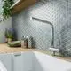 Küchenarmatur mit hohem Auslauf in Chrom, montiert über einer weißen Spüle, vor einem geometrischen Mosaikfliesenhintergrund. Ideal Standard.